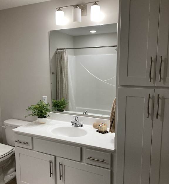 a small bathroom with white cabinets and a sink and a mirror