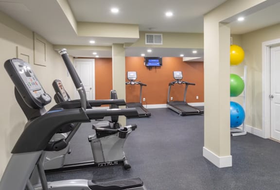 A gym with a treadmill, exercise bike, and elliptical trainer.