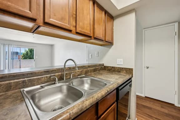 A kitchen with a double sink and wooden cabinets.