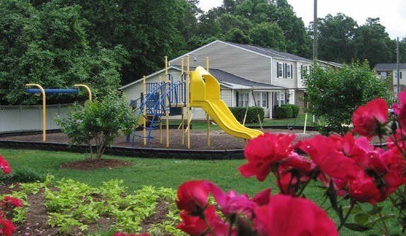 a yellow slide in a park with red flowers at Colony Townhomes, Raleigh, 27609