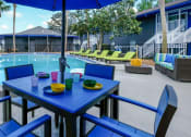 Thumbnail 2 of 23 - View of Community pool from blue patio table with umbrella and chairs. Pool is in the middle of Mandarin Bay Apartments in Jacksonville, 32257
