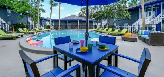 View of Community pool from blue patio table with umbrella and chairs. Pool is in the middle of Mandarin Bay Apartments in Jacksonville, 32257