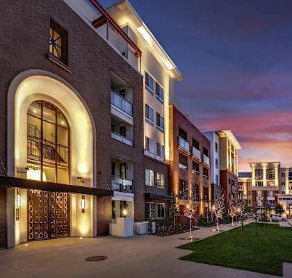 A modern building with a large arched entrance and a well-lit courtyard. at West Park Apartments, San Diego, California