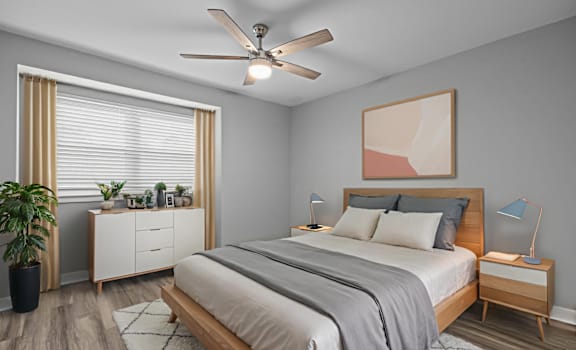 A bedroom with a bed, nightstands, and a ceiling fan.