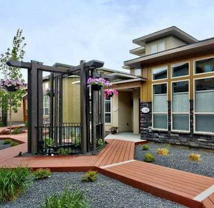 A modern house with a wooden deck and a black gate.