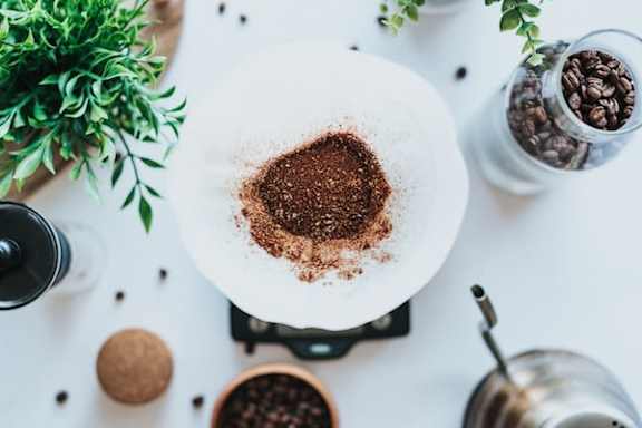 A white plate with a pile of ground coffee on top of a stove.