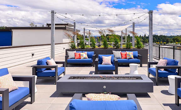 a lounge area on the roof of a building with blue couches and chairs