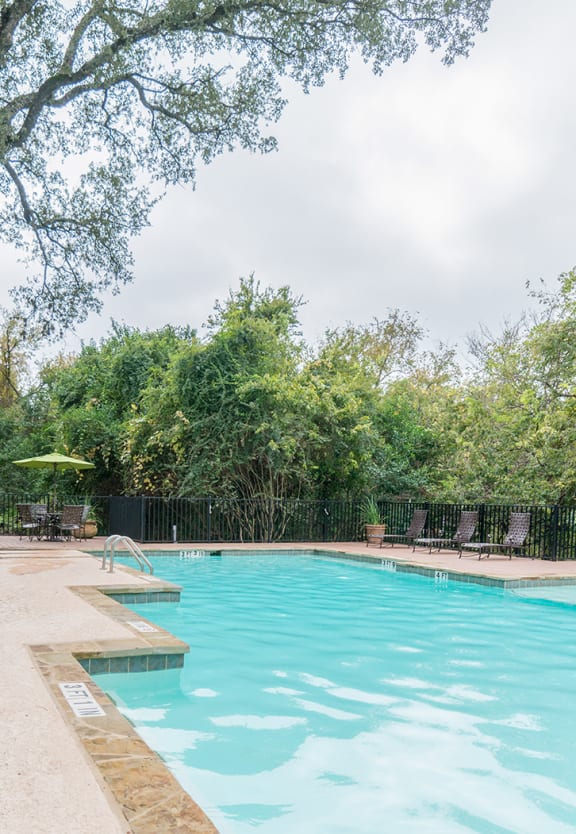 the pool is next to a house with chairs and a resort style pool at High Oaks, Texas, 78759