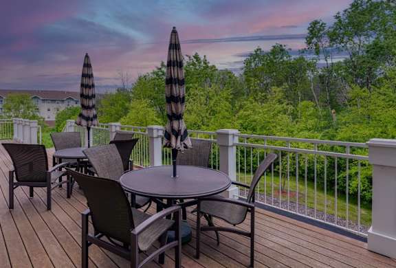 A deck with a table and chairs overlooking a forest.