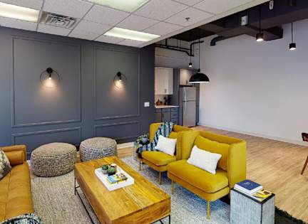 A living room with a yellow couch and a wooden coffee table.