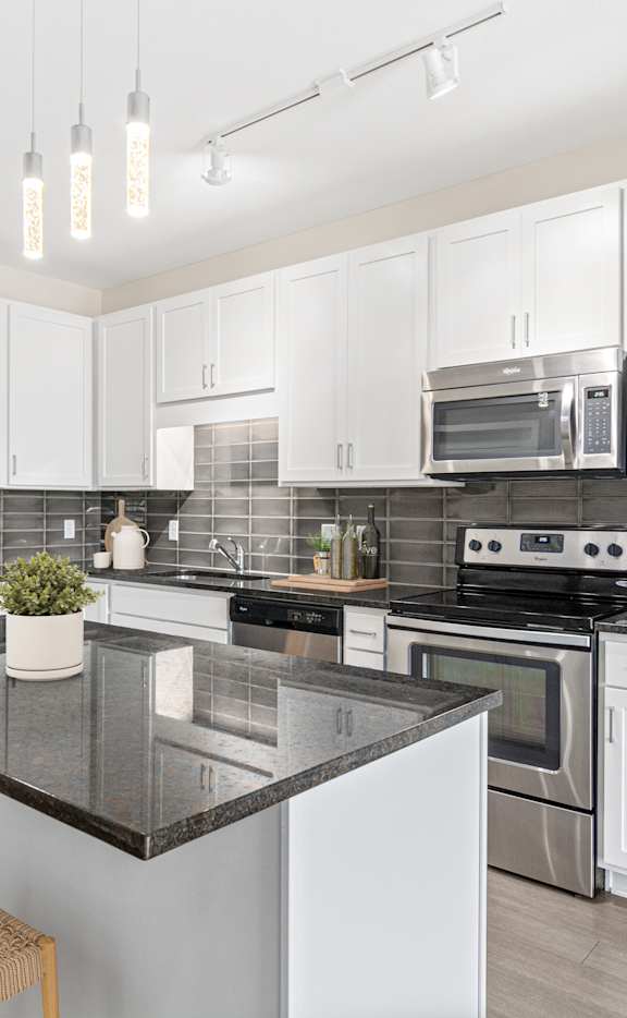 A modern kitchen with a black countertop and stainless steel appliances.
