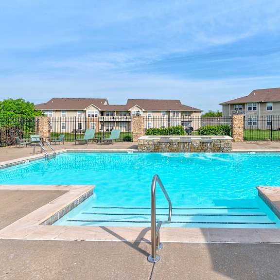 A large swimming pool in front of a building with a clear blue sky above.
