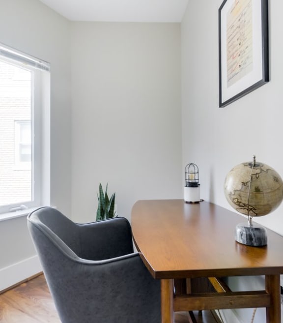 a desk with a chair and globe in a room with two windows
