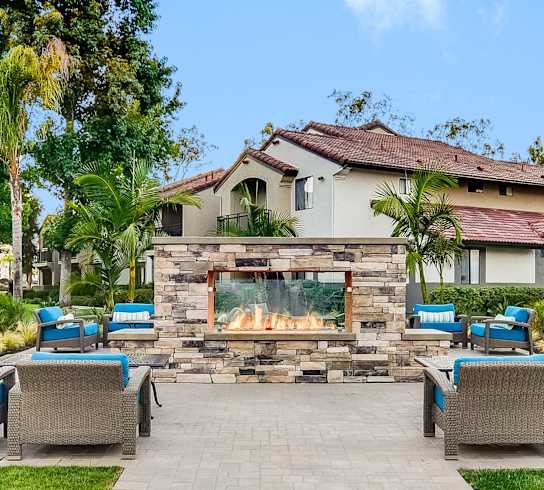 a patio with chairs and tables and a fire pit