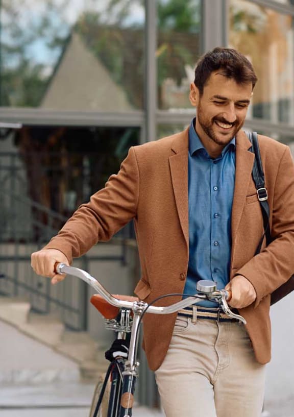 a man in a brown jacket riding a bike