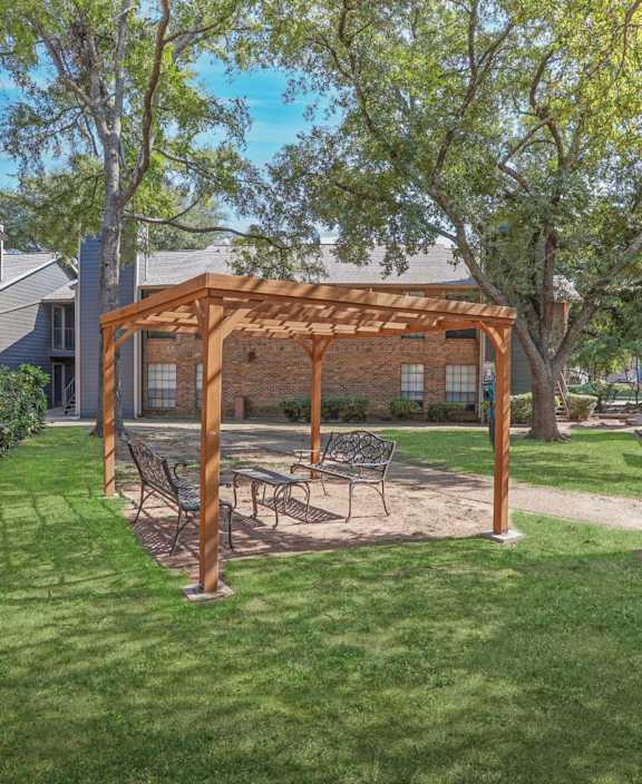 A backyard with a swing set and a wooden pergola.