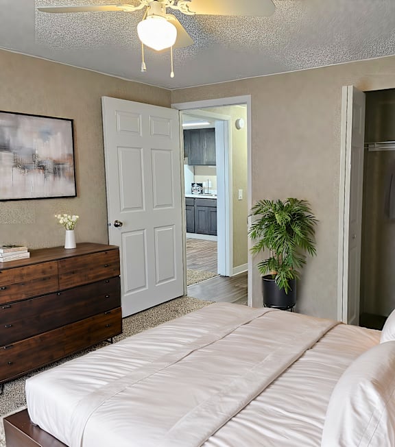 A bedroom with a bed, dresser, and coat rack.