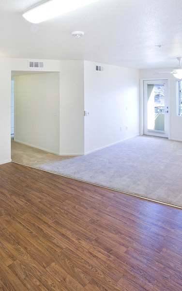 A kitchen with a refrigerator, sink, and wooden floors.