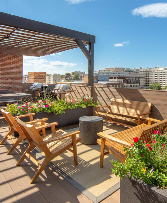 a roof terrace with wooden furniture and a city in the background