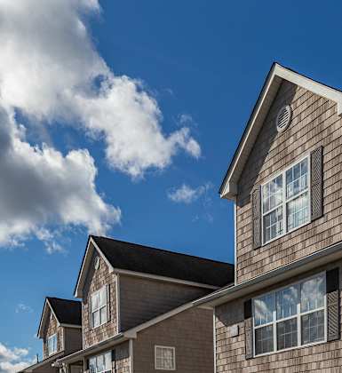 A row of houses with a blue sky and clouds in the background.