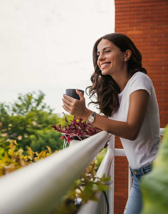 A woman is standing on a balcony holding a camera.