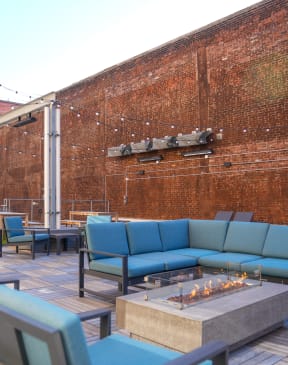 a rooftop patio with blue couches and chairs and a fire pit at East 4th Street, Cleveland, 44115