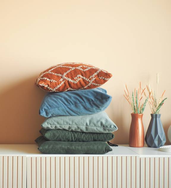 A stack of pillows and a chess set on a radiator.