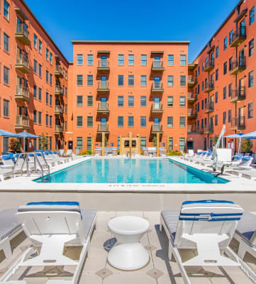 Baxly's swimming pool with chaise lounge chairs and umbrellas in front of an apartment building