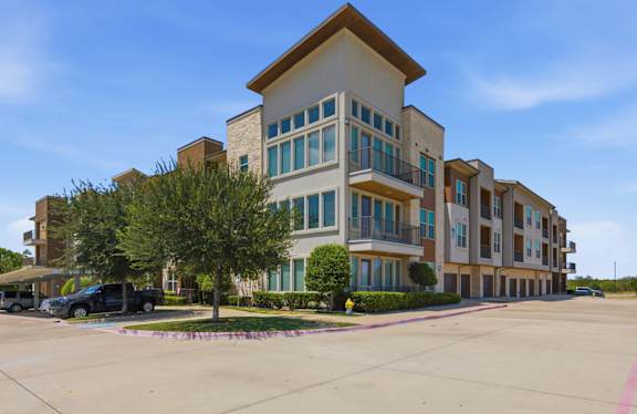 A large apartment complex with a parking lot in front.