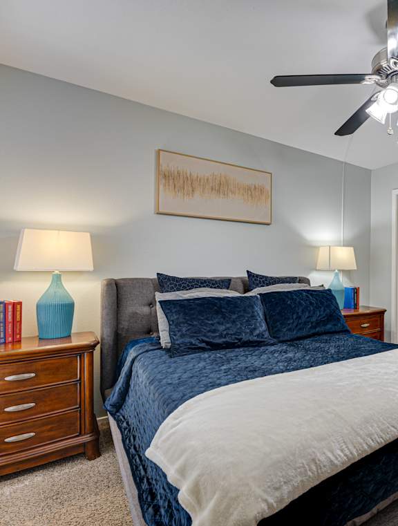 A bedroom with a bed, nightstand, and a ceiling fan.