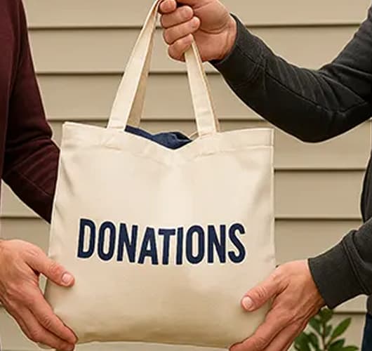 A bag with the word "DONATIONS" printed on it is being held by two people.
