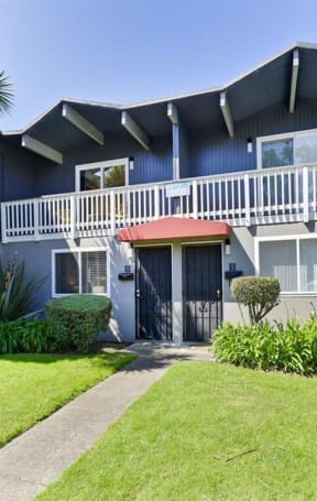 the front of a blue house with a yard and a red umbrella  at The Preston at Hillsdale, San Mateo, CA