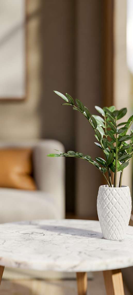 A white vase with a plant in it sits on a marble table.