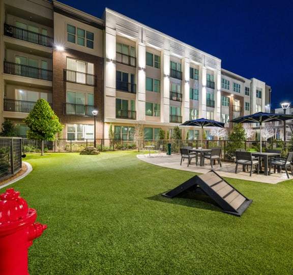 a red fire hydrant sitting on a green lawn in front of an apartment building