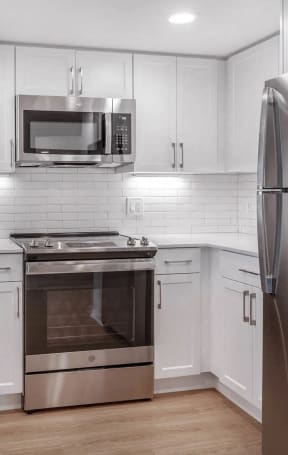 a white kitchen with stainless steel appliances and white cabinets at Avenue Two Apartments, Redwood City, CA