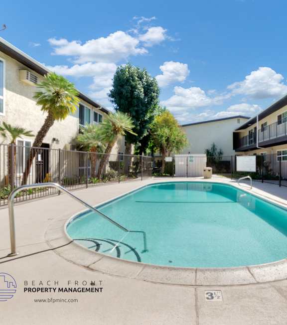 A pool with a hot tub and lounge chairs in front of a building.