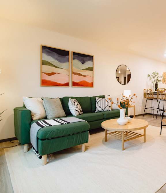 A living room with a green sofa and a wooden coffee table.