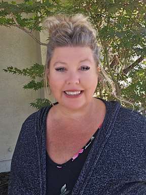 A woman with blonde hair tied up in a bun is smiling.