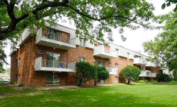 Apartment building with balconies and trees in front.