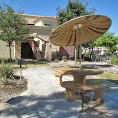 A patio with a table and umbrella in front of a building.