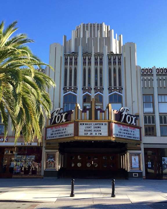 A palm tree stands in front of a building with a sign that says "Fox".