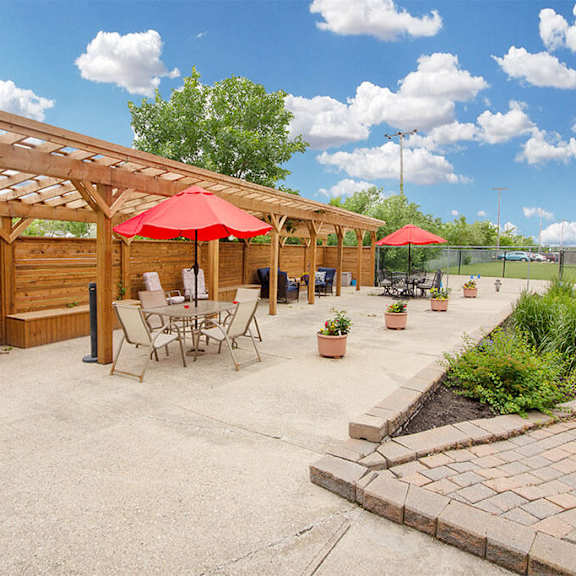 A patio with a table and chairs under a red umbrella.