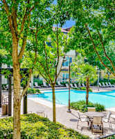 A pool surrounded by trees and chairs.