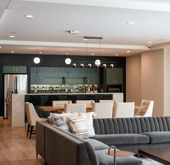 A modern kitchen with a white island and brown chairs.