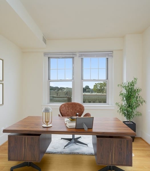 a home office with a wooden desk and a chair in front of two windows at 1841 Columbia Road Apartments, Washington, Washington DC