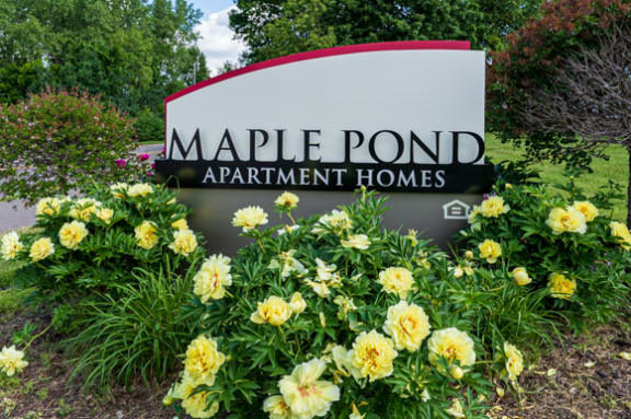 a sign for maple point apartments with yellow and white flowers