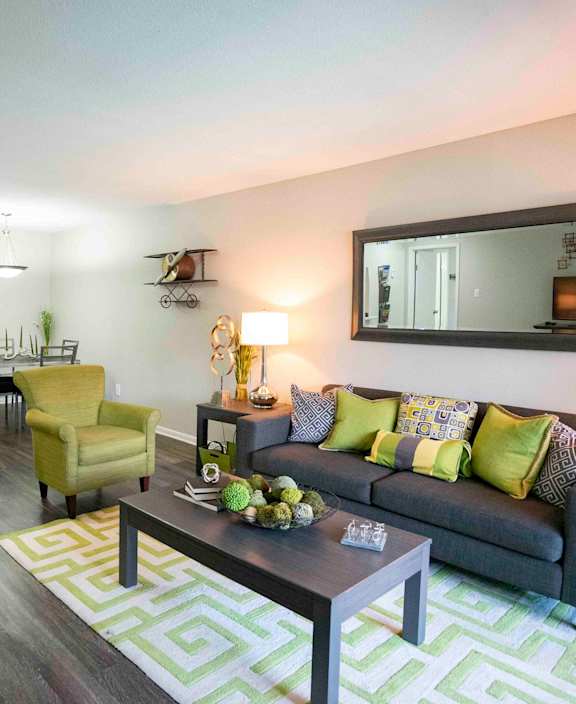 A living room with a grey couch, yellow chair, and a green rug.