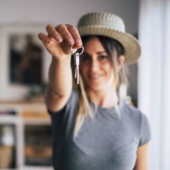 a woman holding up a keys to her hat