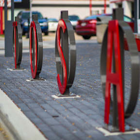 A series of red and black circular objects are displayed on a brick surface.