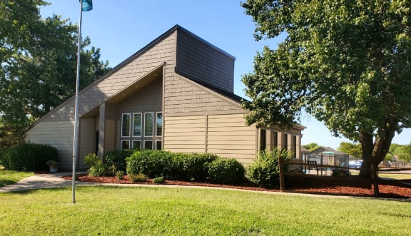 Willow Creek Apartments - Exterior view of the clubhouse with lush landscaping.